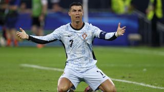 Cristiano Ronaldo, in Portugals light blue and white away kit, frustrated on his knees at Euro 2024.